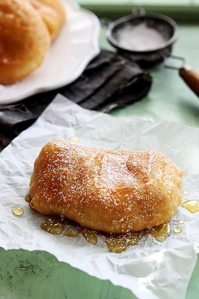a fried scone topped with honey and powdered sugar.