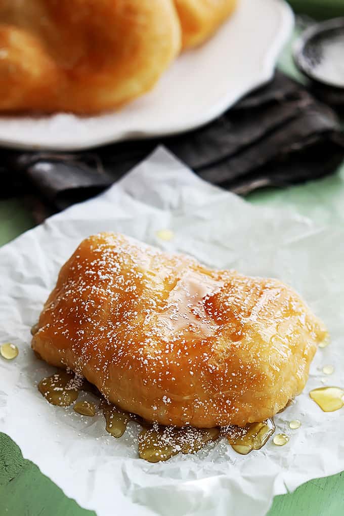 a fried scone topped with honey and powdered sugar.