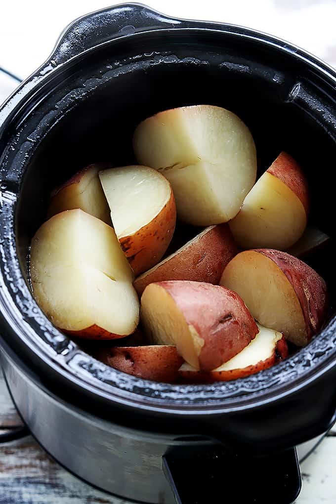 top view of raw cut up potatoes in a slow cooker.