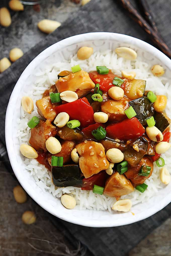 top view of slow cooker kung pao chicken on rice in a bowl topped with peanuts.