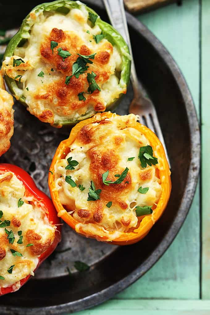 top view of three cheese macaroni stuffed peppers with a fork on the side all on a round serving tray.