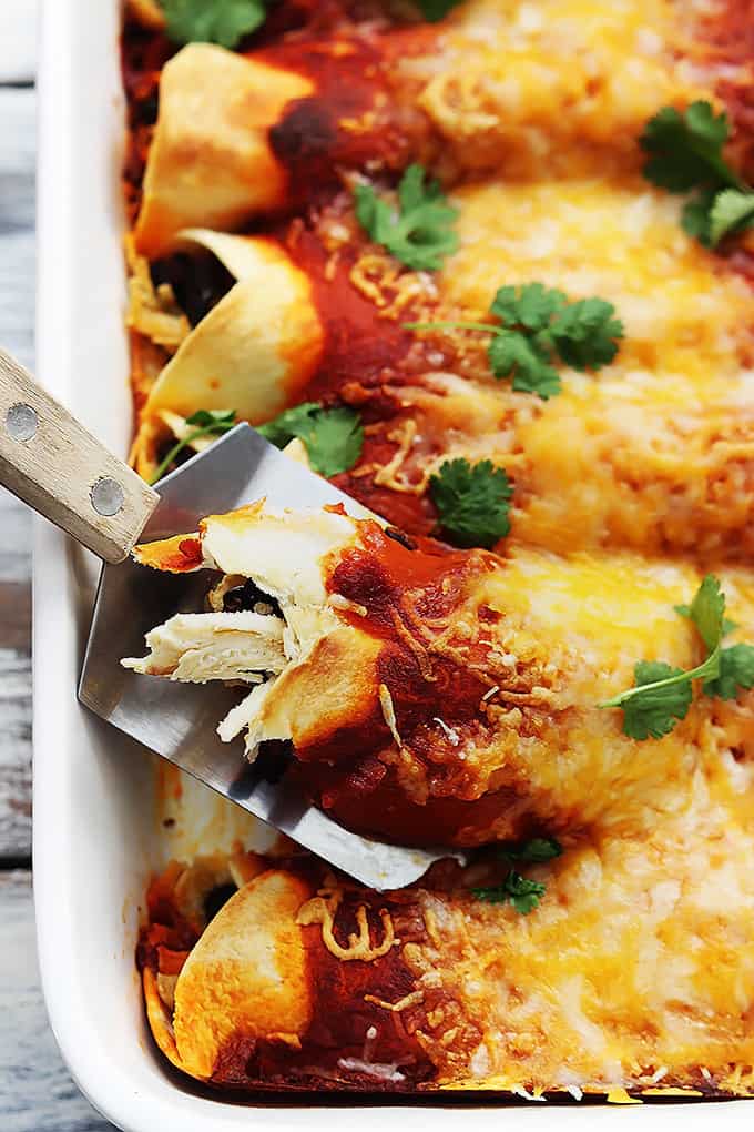 close up of a spatula picking up a turkey enchilada from a baking dish.