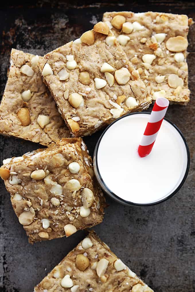 top view of white chocolate chip macadamia nut blondies and a glass of milk with a straw.