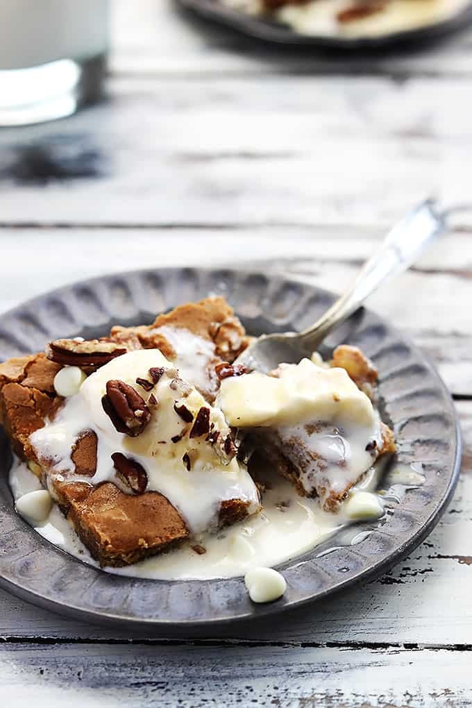 Applebee's maple nut blondie with cream sauce on a plate with a fork inbetween the blondie and a bite of the blondie.