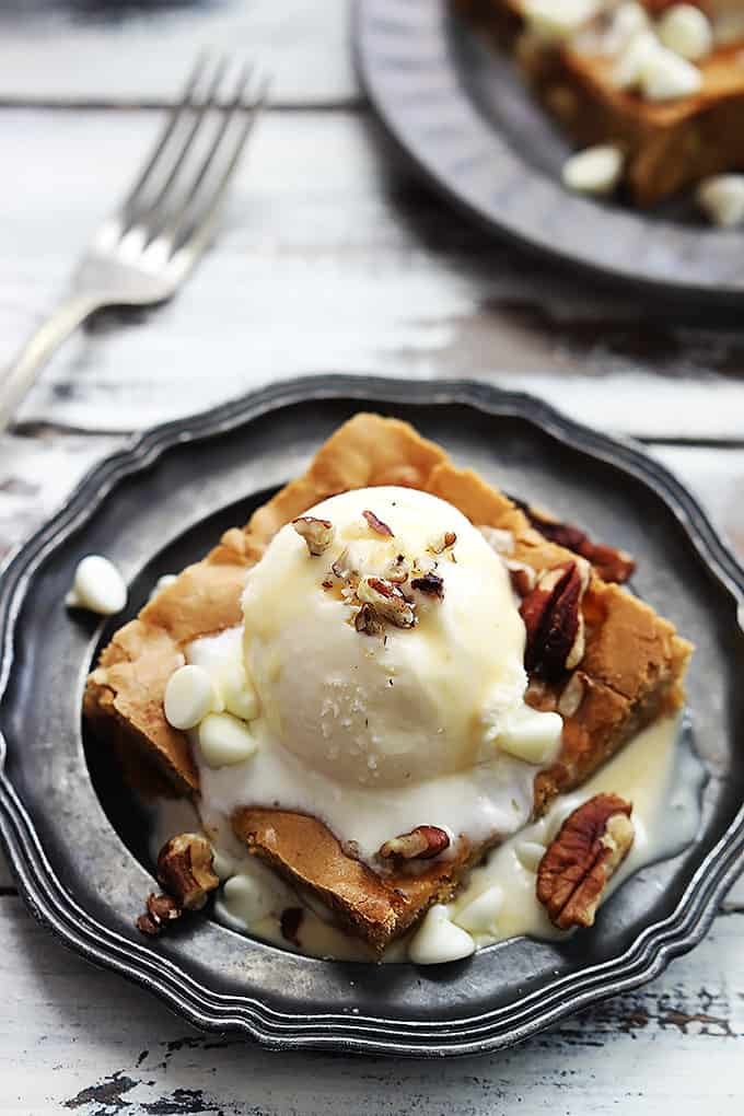 Applebee's maple nut blondie with cream sauce on a plate with a fork and another blondie on a plate in the background.