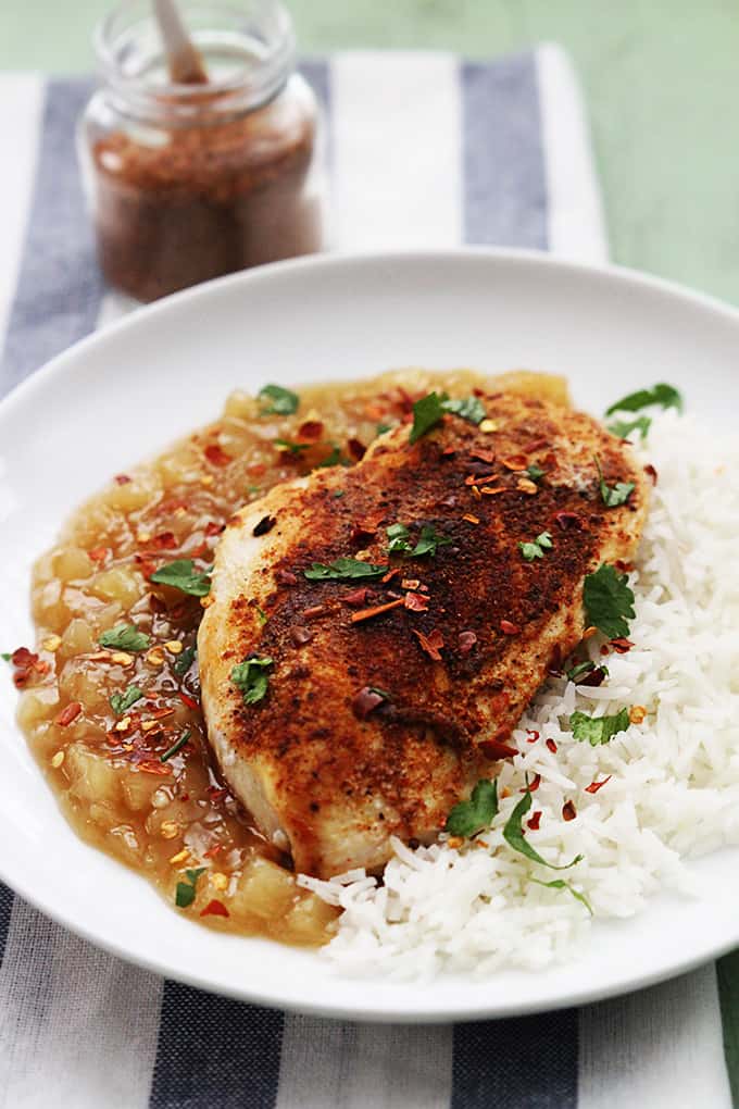 Bahama mama chicken with rice on a plate with a jar of spices in the background.