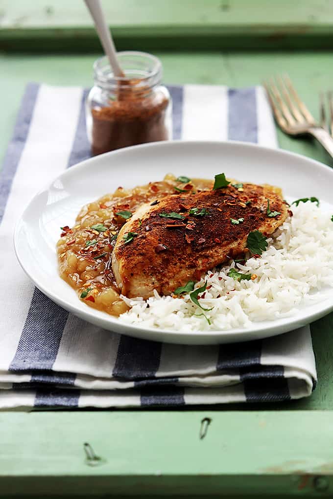 Bahama mama chicken with rice on a plate with a fork and a jar of spices in the background.