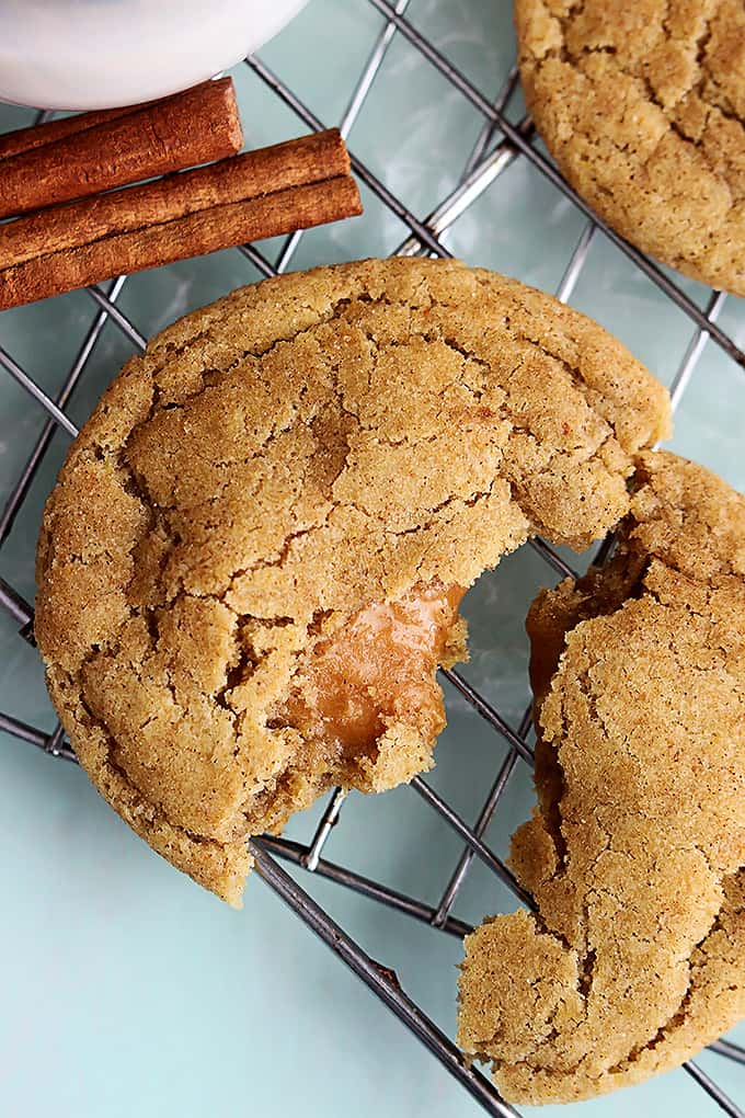 close up of a caramel stuffed snickerdoodle broken in half on a cooling rack.