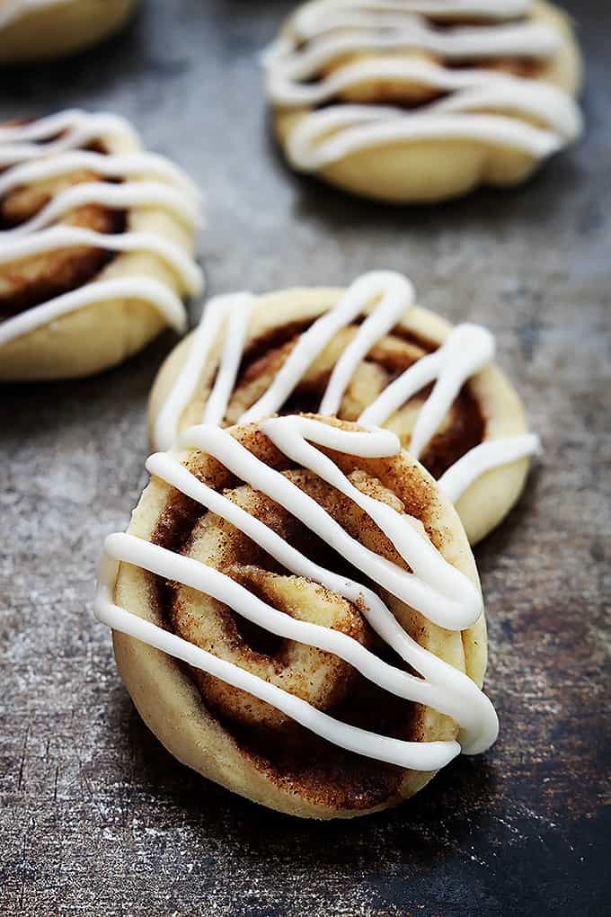 stacked cinnamon roll cookies with more cookies in the background.