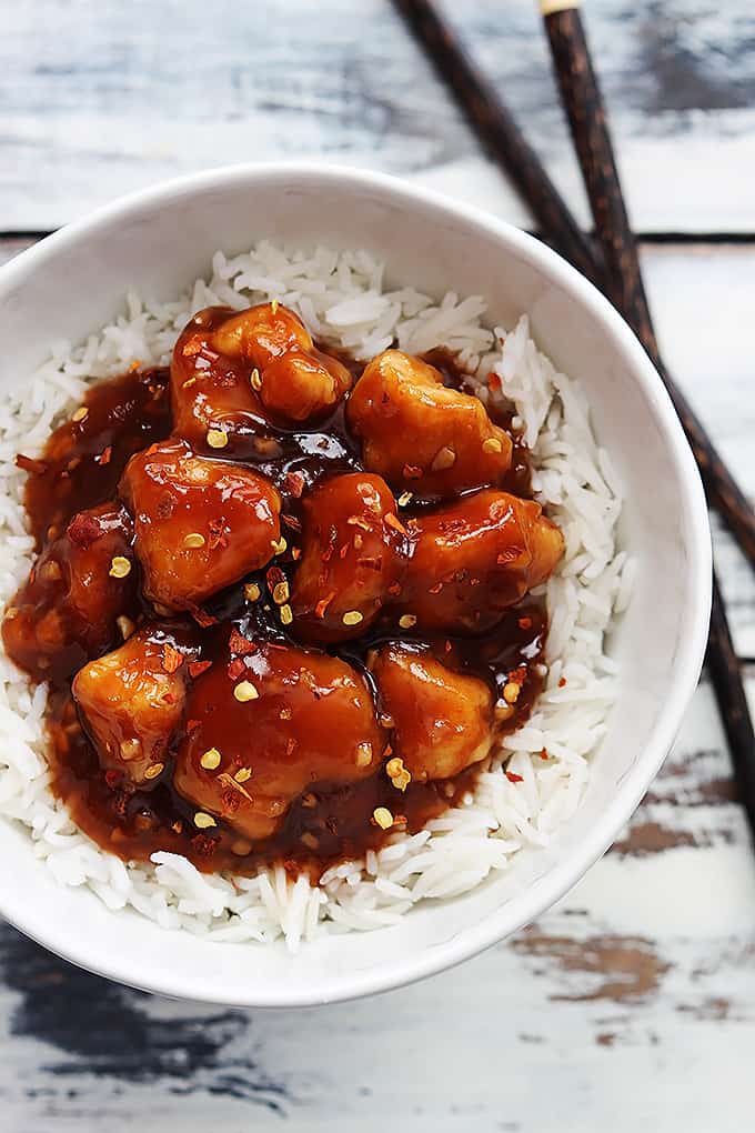 top view of honey sriracha chicken on rice in a bowl with chopsticks on the side.