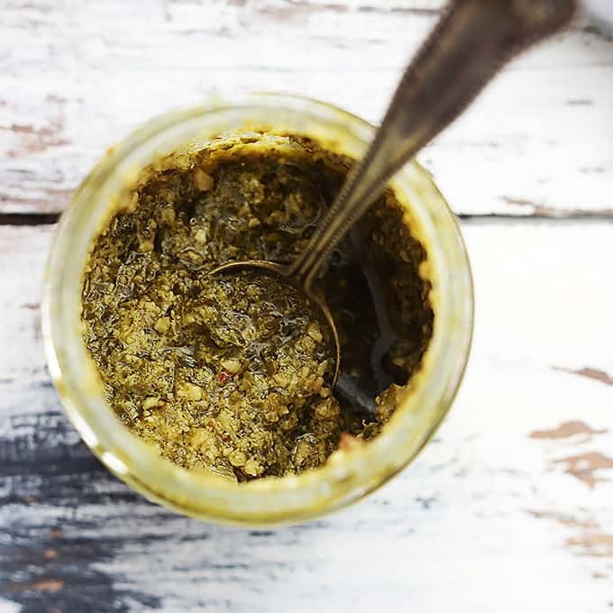 top view of a jar of pesto with a spoon inside.