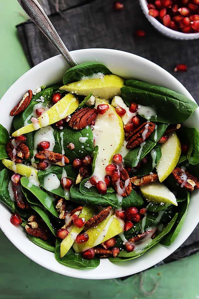 top view of pomegranate pear & pecan salad with poppyseed dressing with a fork in a bowl.