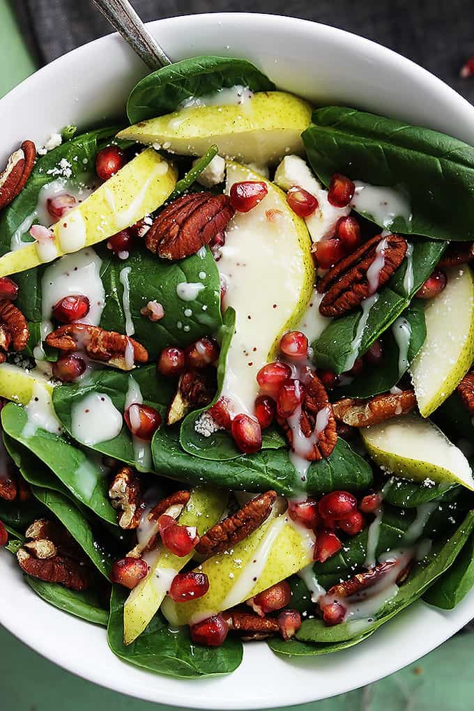 close up top view of pomegranate pear & pecan salad with poppyseed dressing in a bowl.