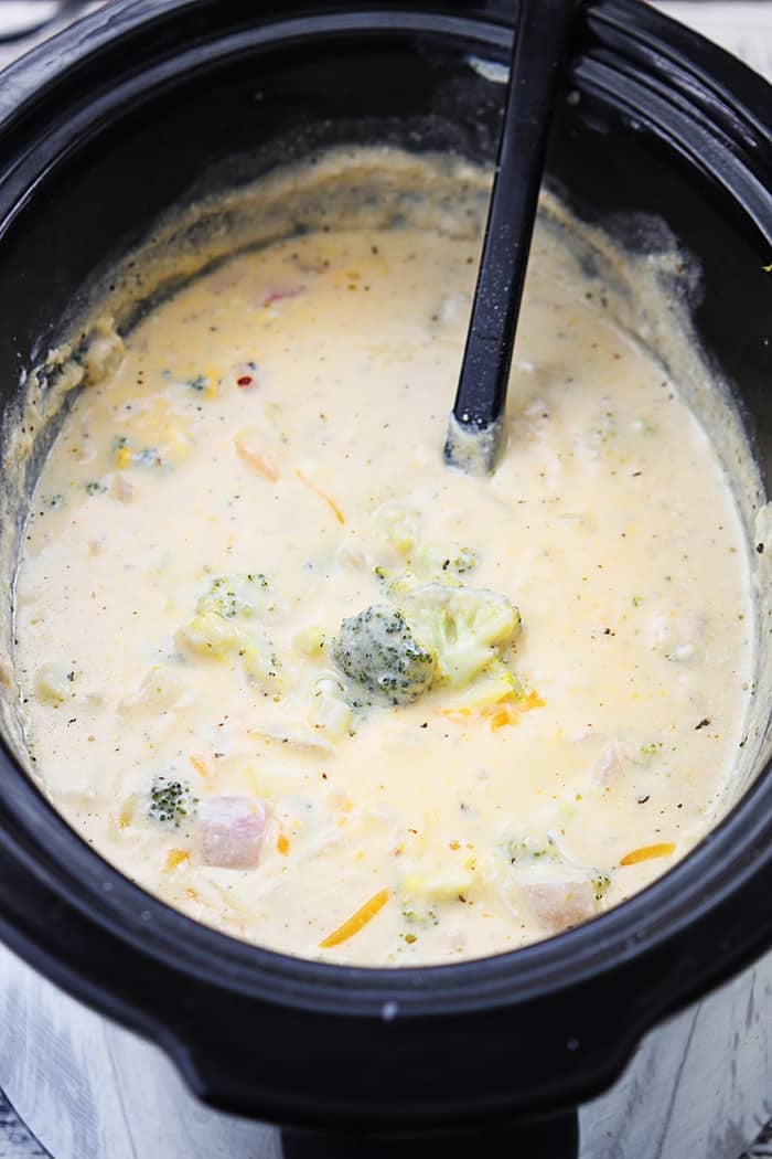 slow cooker broccoli cheese soup in a slow cooker with a serving spoon.