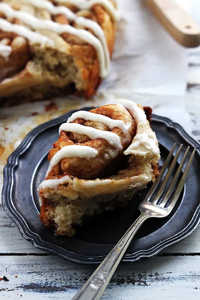 a slow cooker cinnamon roll on a plate with a fork.