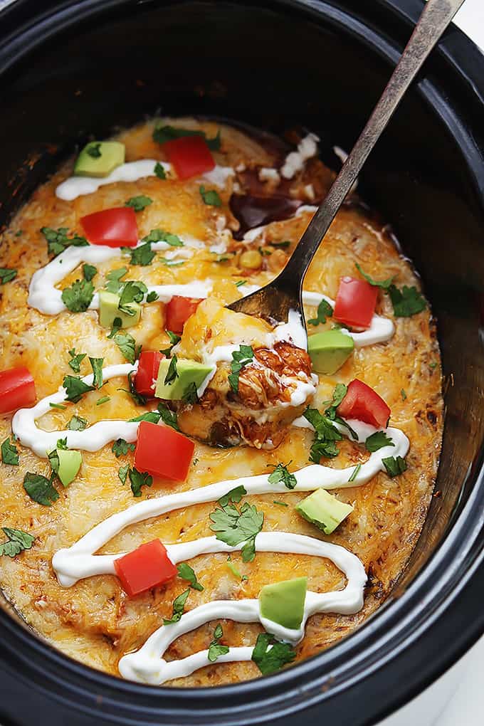 top view of slow cooker enchilada quinoa and a serving spoon in a slow cooker.