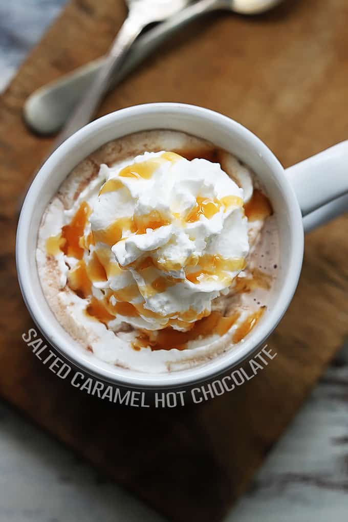 top view of slow cooker salted caramel hot chocolate in a mug topped with whipped cream and caramel with the title of the recipe written around the bottom part of the mug.