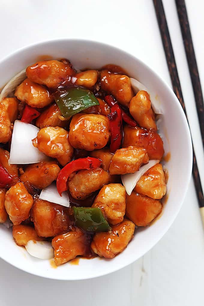 top view of sweet and sour chicken in a bowl with chopsticks on the side.