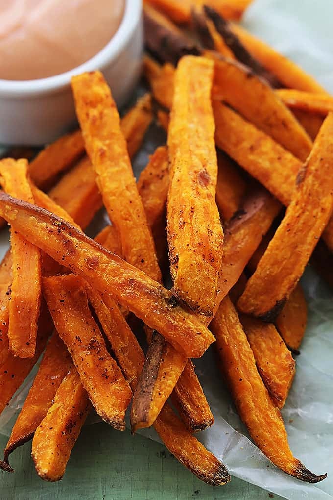 close up of sweet potato fries with a small bowl of fry sauce on the side.