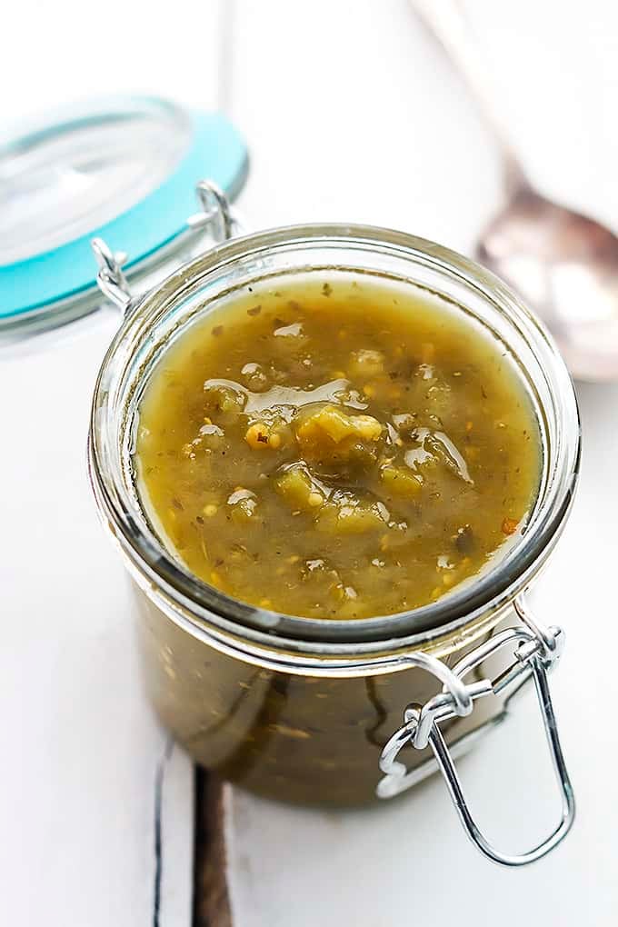 salsa verde in a jar with a spoon faded in the background.