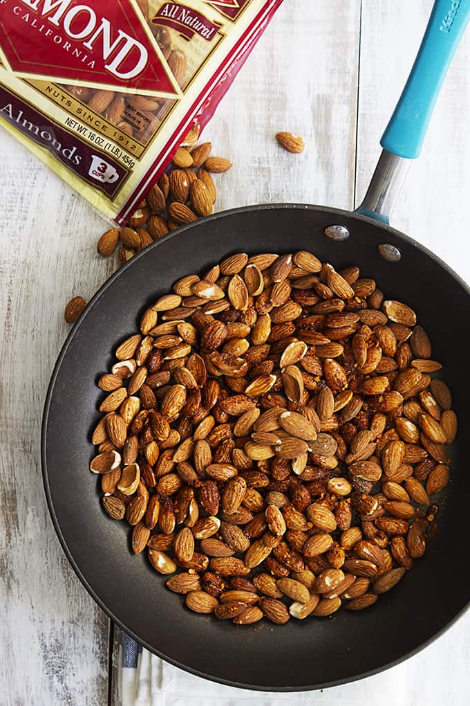 top view of chili lime almonds in a skillet with a bag of almonds on the side.