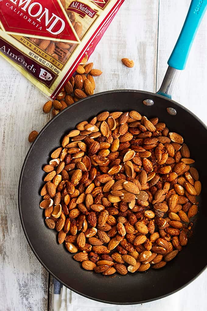 top view of chili lime almonds in a skillet with a bag of almonds on the side.