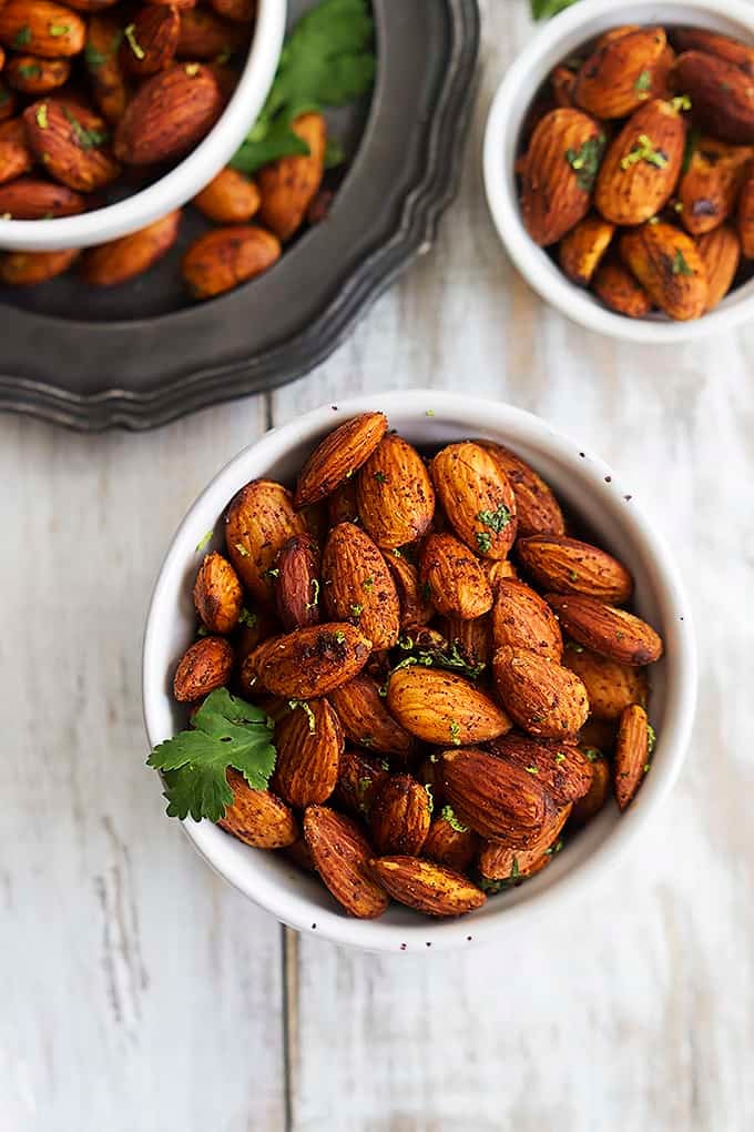 top view of chili lime almonds in a small bowl with more small bowls full of almonds on the side.