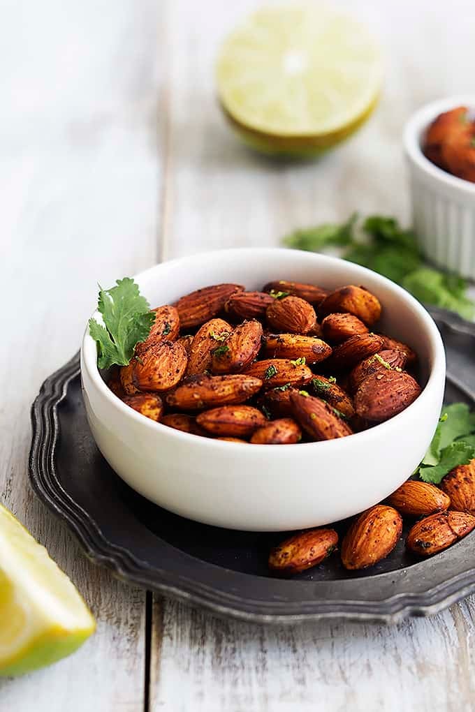 chili lime almonds  in a small bowl with limes on the side.