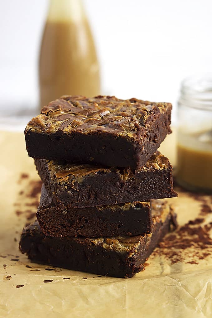stacked Dulce de Leche brownies with jars of Dulce de Leche sauce in the background.
