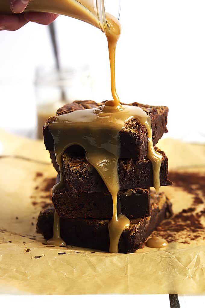 stacked Dulce de Leche brownies with Dulce de Leche sauce being poured on top.