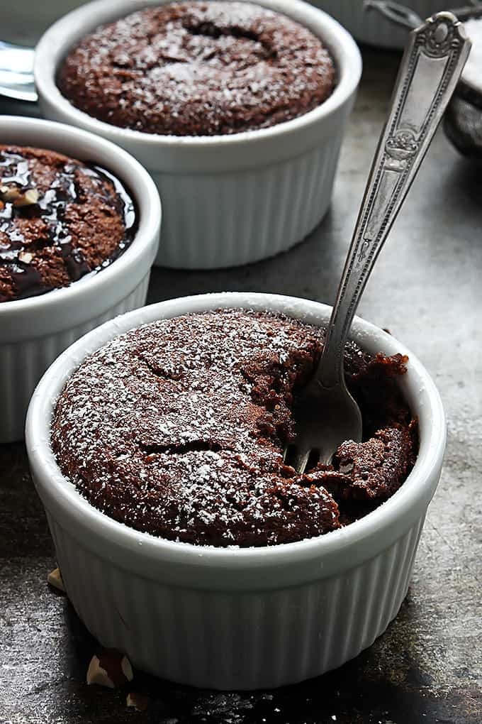 a fork in a bowl of flourless chocolate almond cake with more bowls of cake in the background.