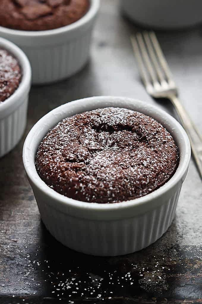 flourless chocolate almond cake in a small bowl with more bowls of cake and a fork in the background.