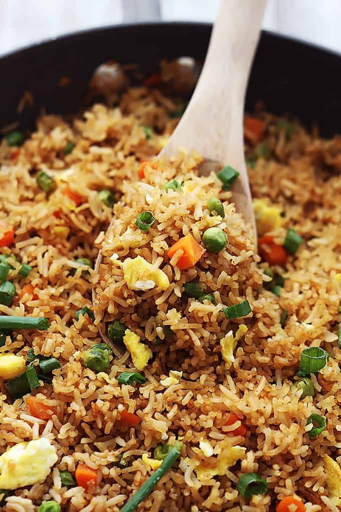 a skillet full of fried rice with a wooden serving spoon.