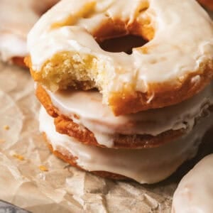 A stack of old fashioned sour cream donuts with the top one missing a bite.
