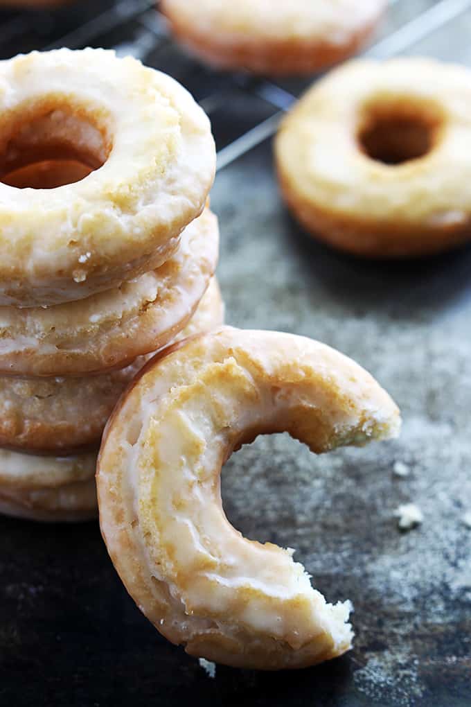 stacked old fashioned sour cream donuts with another donut with a bite missing leaning on them.