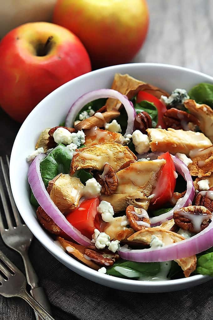 Panera Bread's Fuji apple chicken salad in a bowl with forks and apples on the side.