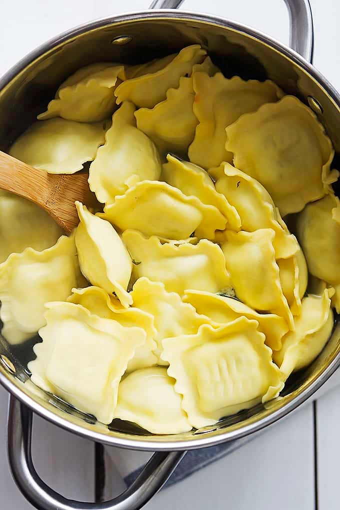 top view of ravioli noodles in a pan with a wooden spoon.
