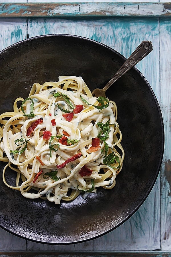 top view of healthy spinach fettuccine with a fork in a bowl.