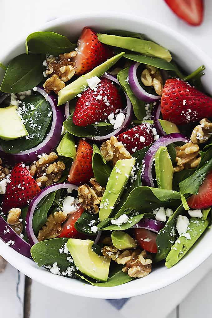 close up top view of strawberry avocado spinach salad in a bowl.
