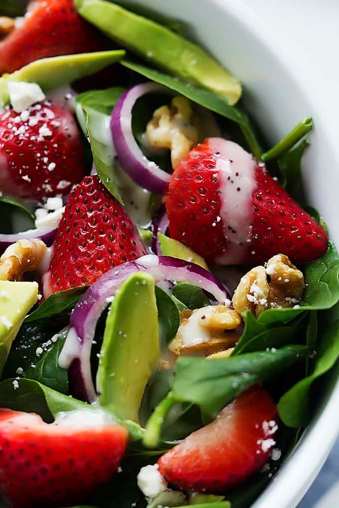 close up of strawberry avocado spinach salad in a bowl.