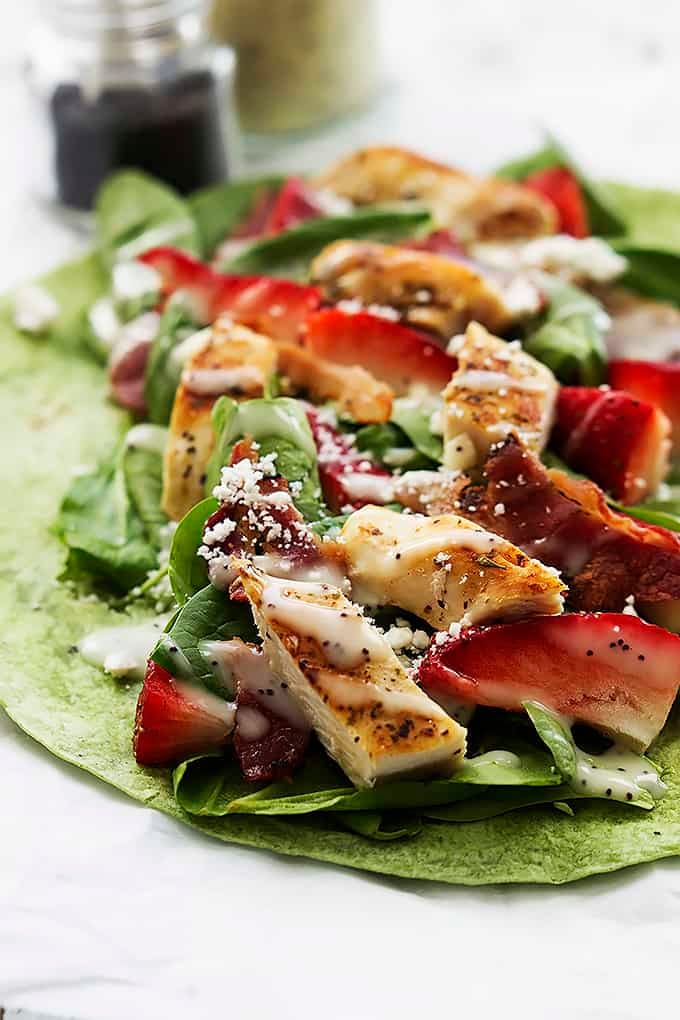 close up of a open strawberry chicken bacon & spinach wrap with poppyseed dressing.