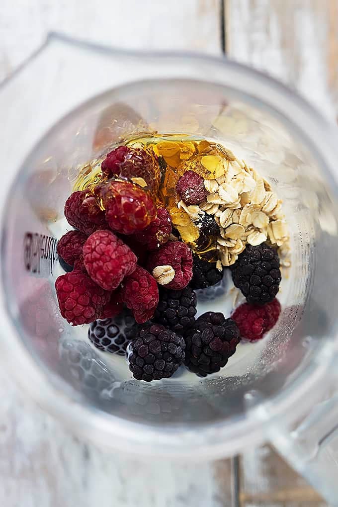 top view of berry oat breakfast smoothie ingredients unmixed in a blender.
