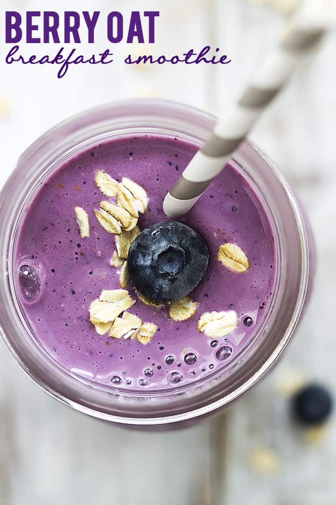 top view of berry oat breakfast smoothie in a jar with a straw and topped with oats and a blueberry with the title of the recipe written on the top left corner of the image.