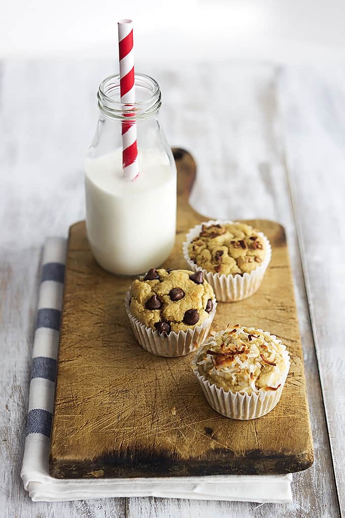 flourless banana blender muffins on a wooden cutting board with a jar of milk and a straw.