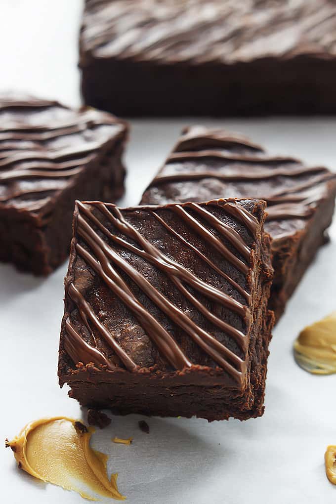 stacked flourless fudgey peanut butter brownies with more brownies in the background.