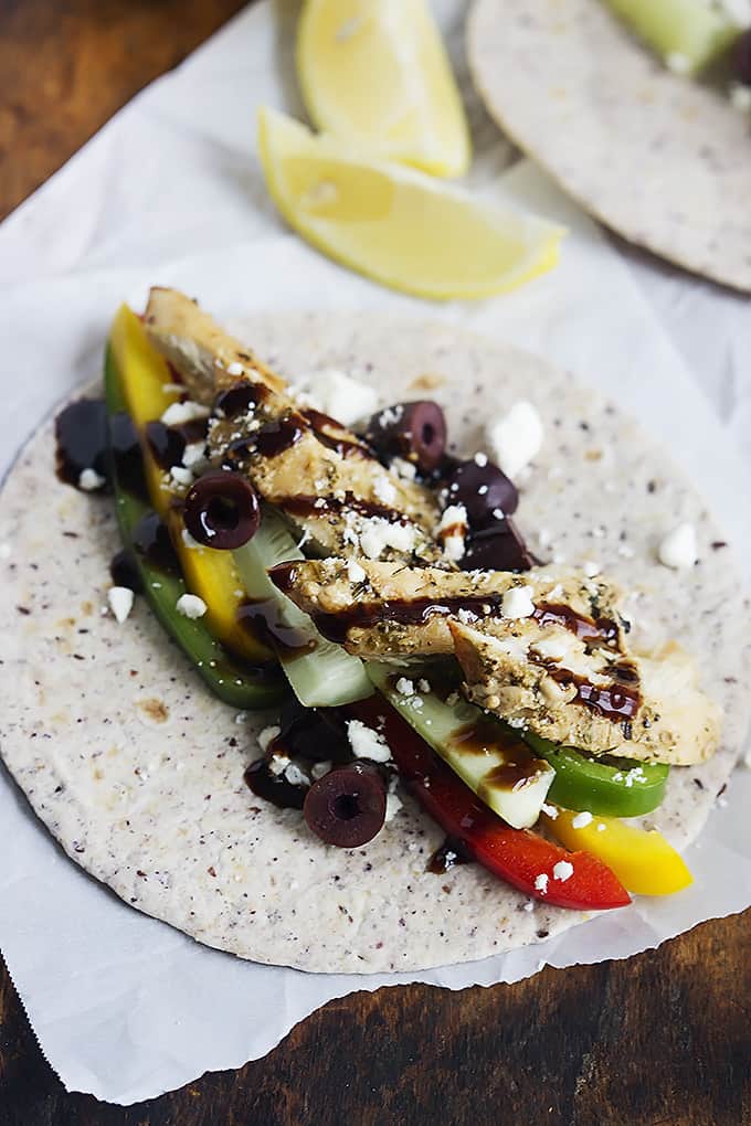 a Greek chicken taco laid flat with lemon slices on the side.