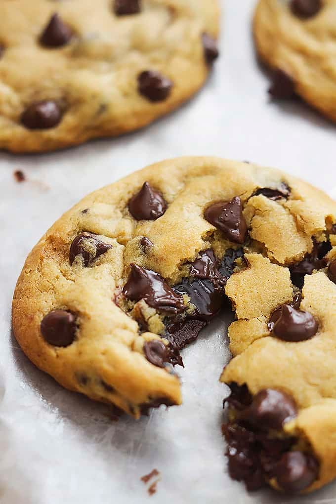 close up of a hot fudge stuffed chocolate chip cookie broken in half with more cookies on the side.