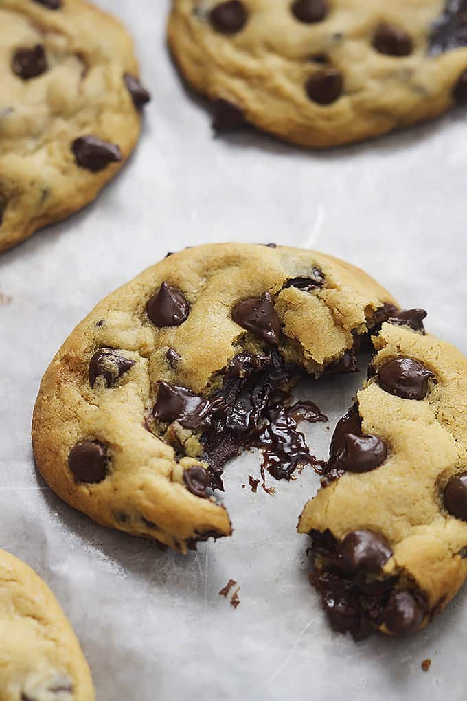 a hot fudge stuffed chocolate chip cookie broken in half with more cookies on the side.