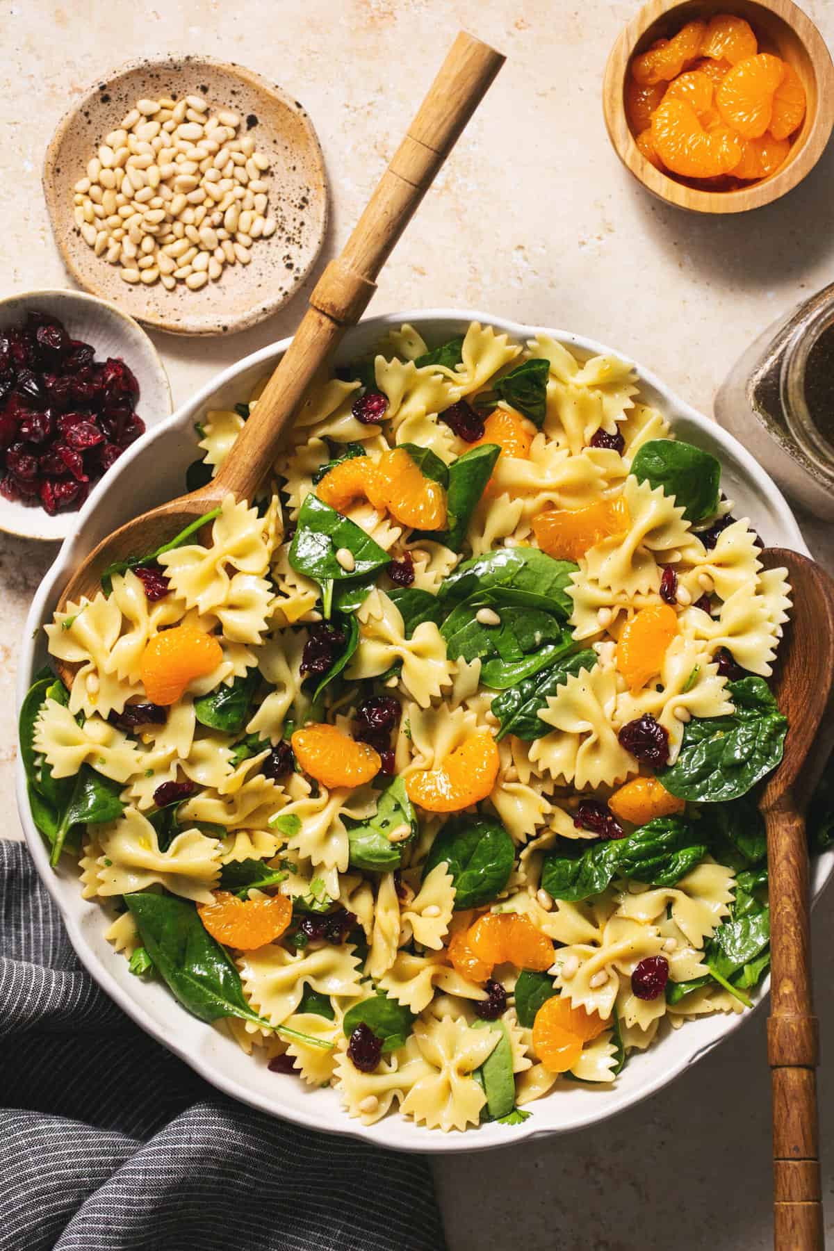 mandarin spinach pasta salad in bowl with serving spoons