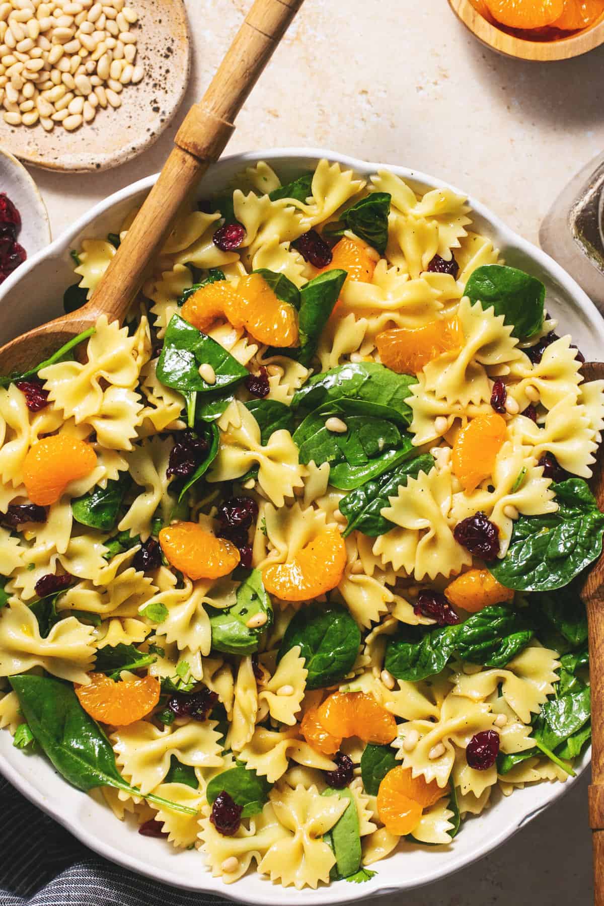mandarin spinach pasta salad in bowl with serving spoons